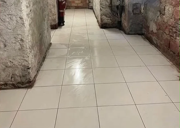 Le même couloir de cave après le nettoyage, carrelage propre et dégagé