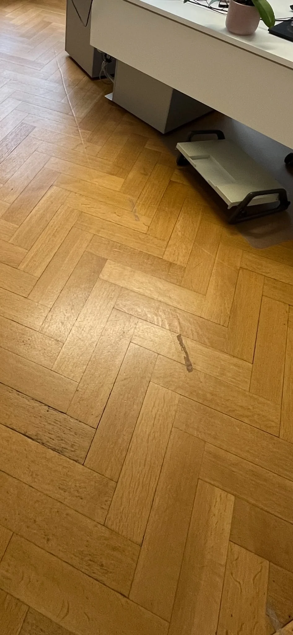 Parquet à bâtons rompus d'un bureau avant la rénovation, rayé et taché près du bureau