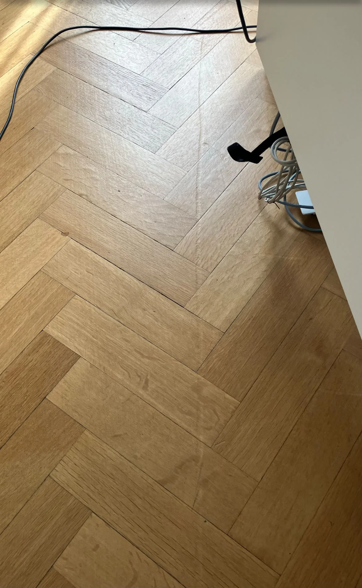 Parquet à bâtons rompus avant la rénovation, rayure en travers des lames et taches