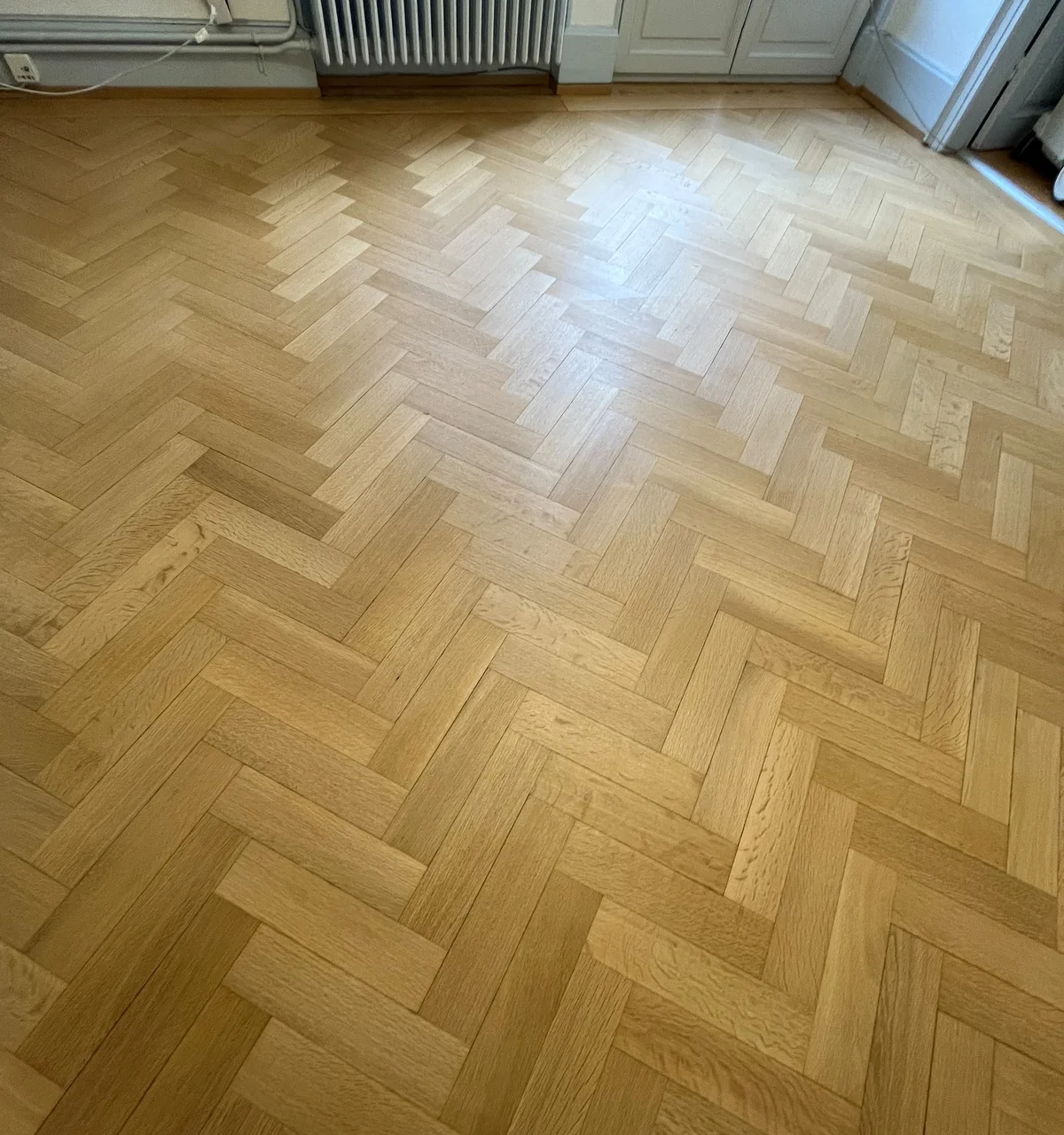 Parquet à bâtons rompus après la rénovation, lames lisses et lumineuses devant la fenêtre