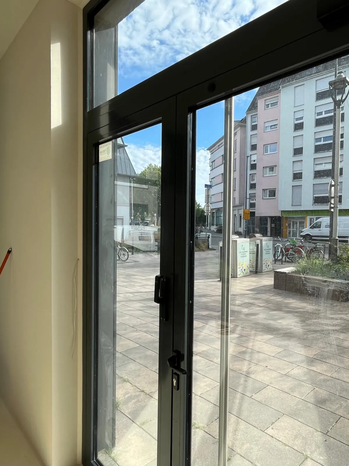 Porte vitrée d'un commerce vue de l'intérieur, vitrage propre donnant sur la place